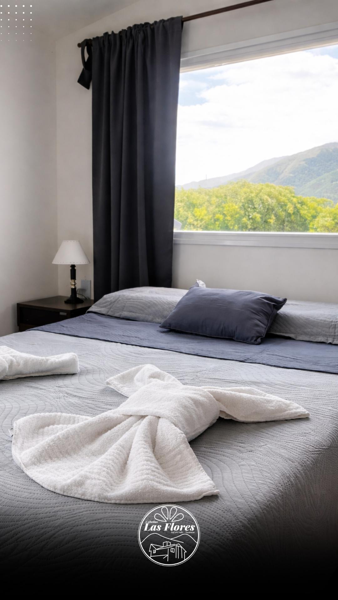 Dormitorio de cabaña premium con cama matrimonial y ventanal con vista a la sierra